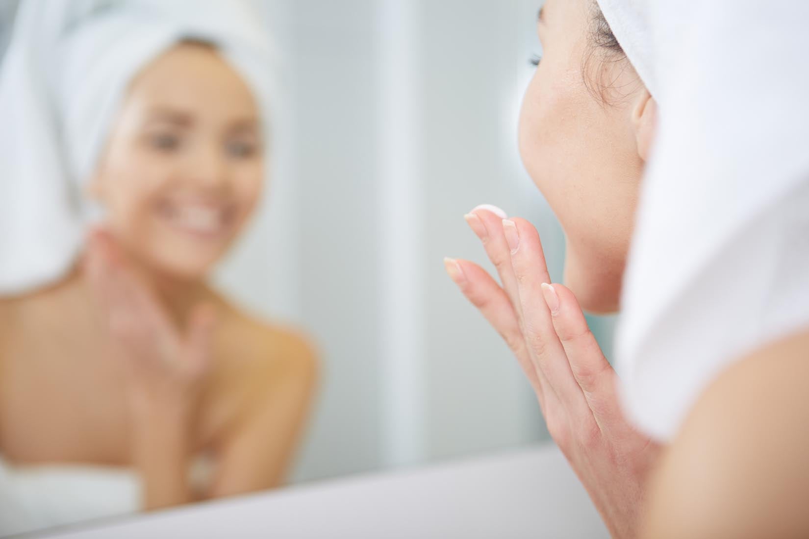 Uma rapariga a limpar o rosto de modo a garantir uma pele saudável